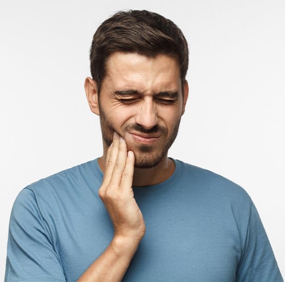 Man in need of tooth extraction holding jaw in pain