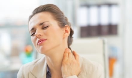 Woman in beige business jacket holding her neck in pain