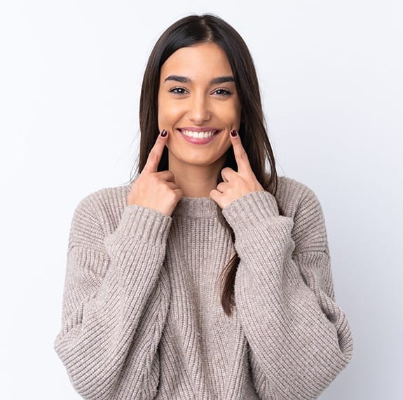 Woman pointing to beautiful smile after visiting her Fairfax dentist