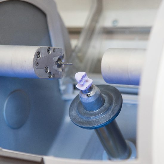 An in-house milling unit creating a custom-made dental crown from porcelain material