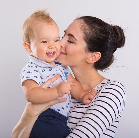 Mother kissing baby on cheek after children's dentistry visit