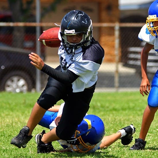 Young boys playing football wearing custom athletic mouthguards