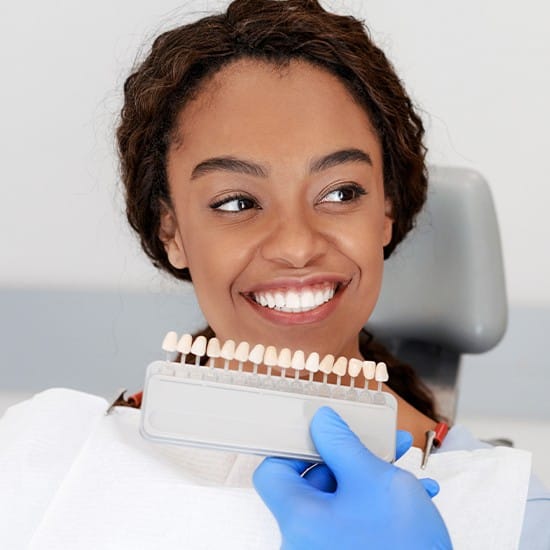 Woman's smile compared with porcelain veneer shade chart