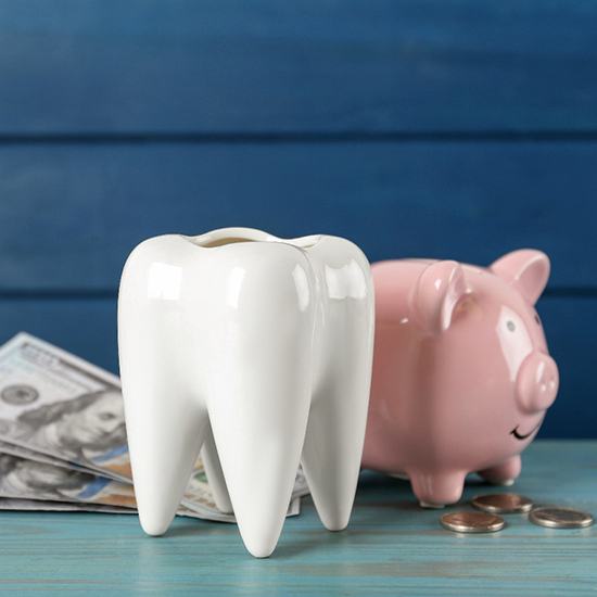 A giant ceramic tooth sitting next to a piggy bank and dollar bills