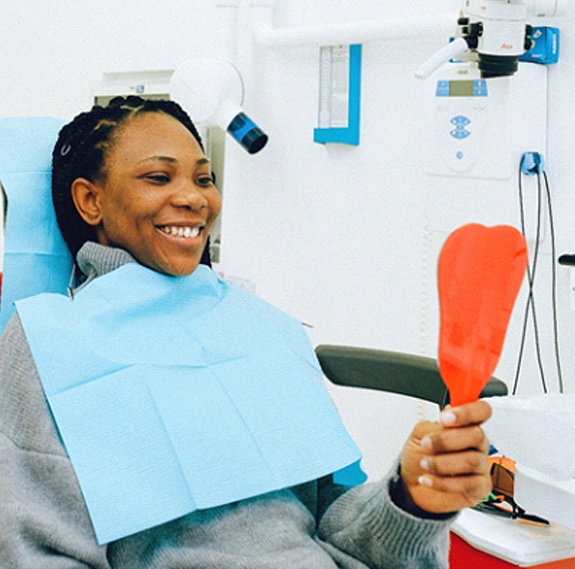 Woman looking in mirror at Delta Dental dentist