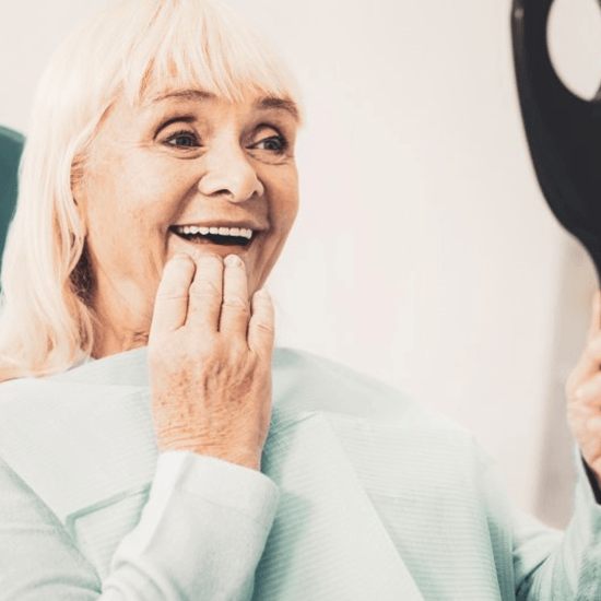 a patient checking out her new dentures in a mirror