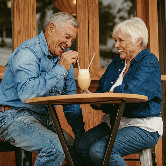 Senior couple with dentures in Fairfax sharing a milkshake