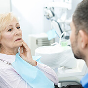 senior woman with toothache talking to her emergency dentist in Fairfax 