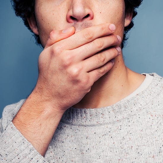 Man in need of tooth extraction covering damaged smile