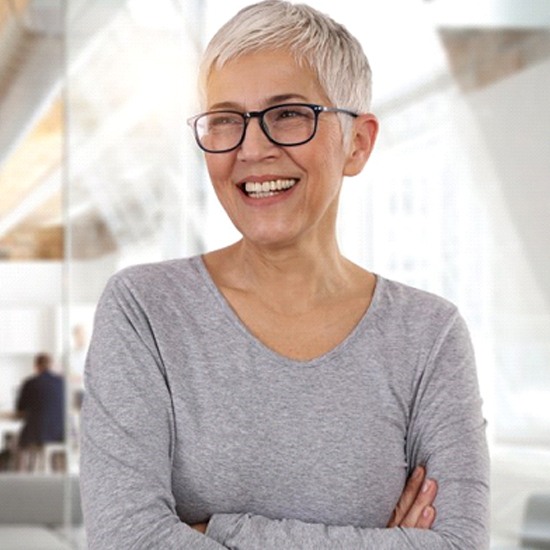 woman in a gray shirt showing off her dental implants in Fairfax