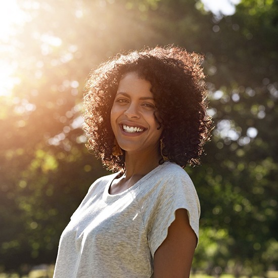 person smiling and taking a walk in a park