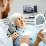 Older woman with dental implants in Fairfax smiling at dentist