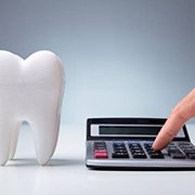 Person touching a calculator with model tooth next to it