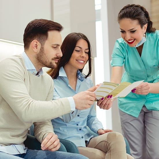 Dental team member handing dentistry patients information about dental insurance coverage