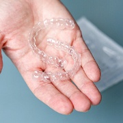 person holding two clear aligners