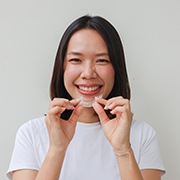 Woman smiling while holding clear aligner