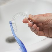 Patient cleaning clear aligner in sink