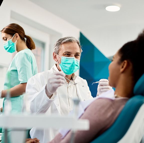 Smiling dentist preparing to examine patient’s teeth