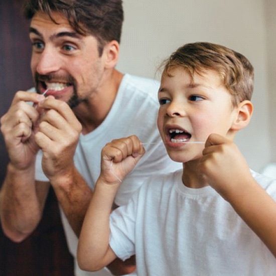 father and young son flossing their teeth together