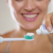 person putting toothpaste onto an electric toothbrush