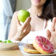 person choosing to eat an apple instead of donuts
