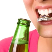person opening a glass bottle with their teeth