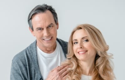 Man and woman smiling after replacing missing teeth