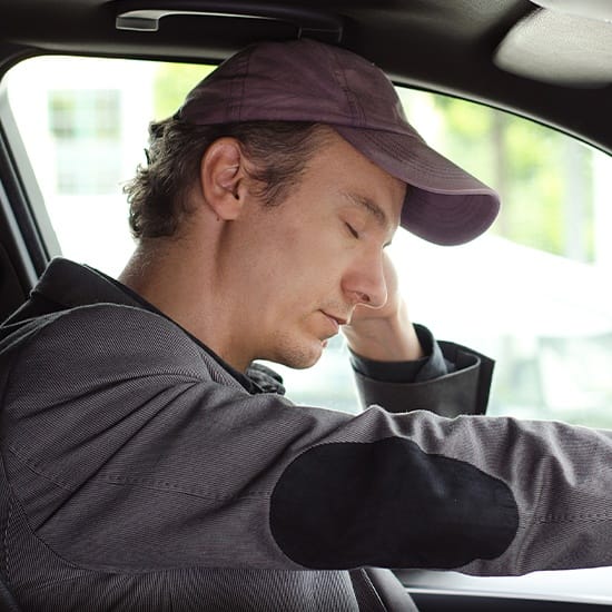 Tired man falling asleep while driving in need of sleep apnea therapy