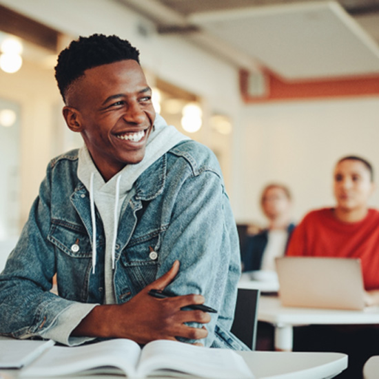 Teen in denim jacket smiling in classroom