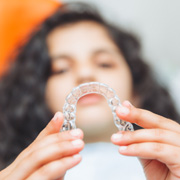 Teenager holding Invisalign aligner in treatment chair