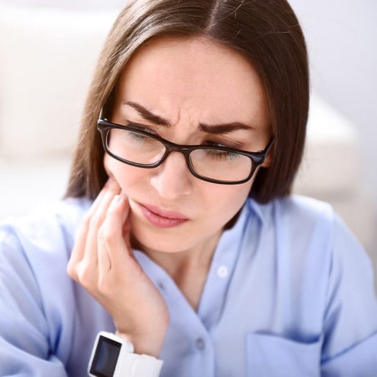 Woman with jaw pain holding cheek