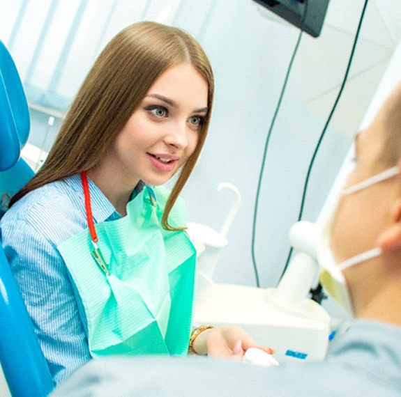 A young woman sits and listens as her dentist explains whether she is a candidate for treatment