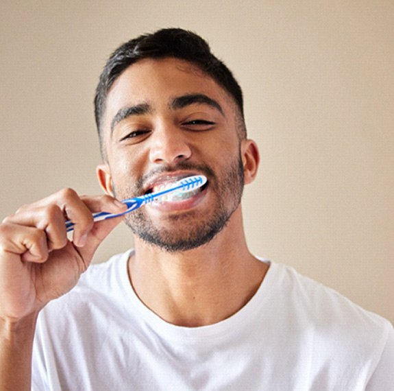 Man in white shirt brushing his teeth