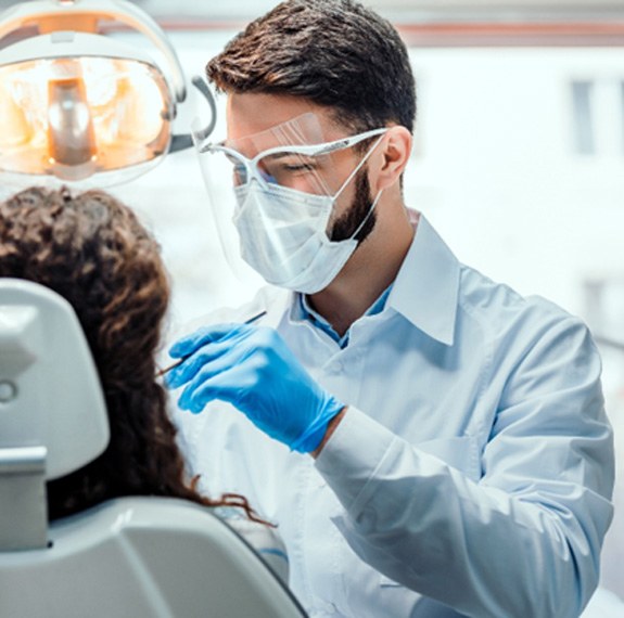 Dentist smiling while conducting procedure in office