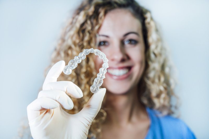 Dentist smiling while holding Invisalign tray