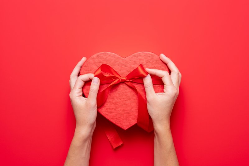 person tying a bow to a heart-shaped box