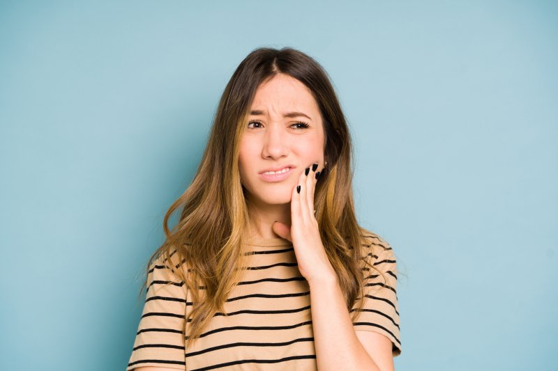 Woman clutching her tooth due to a toothache