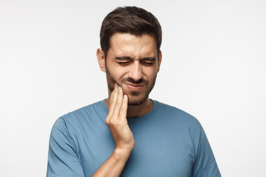person with toothache holding cheek