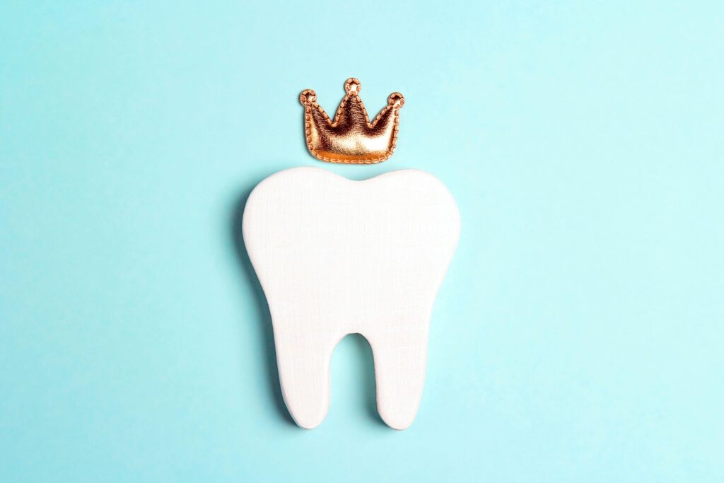 Flat toy tooth on teal background with small toy crown above it