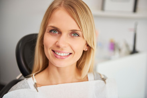Blonde woman sitting in dental chair and smiling